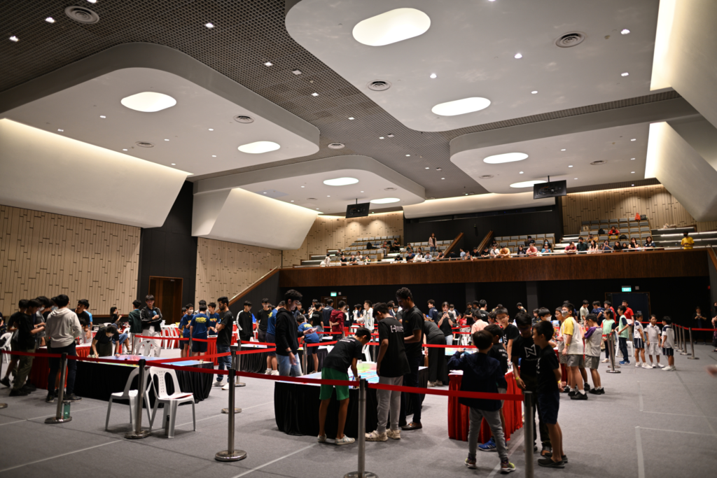 Wide view of WRO Singapore 2023 at Jurong Town Hall, showing students participating in robotics challenges across a large event space.