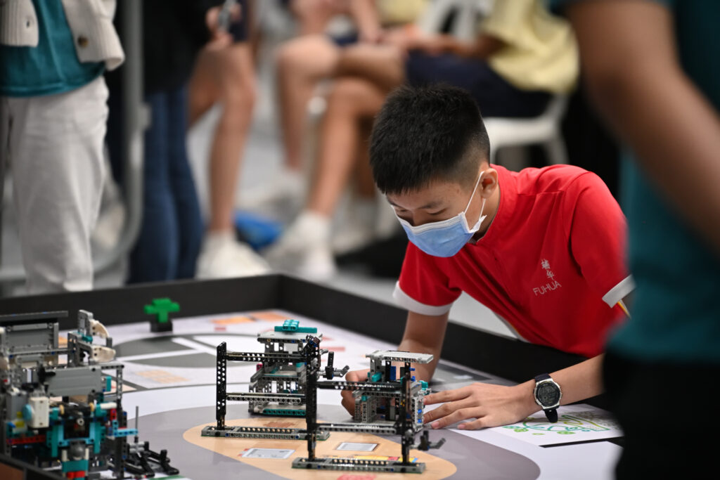 Fuhua Secondary School student programming a LEGO robot on a competition mat at the National Robotics Competition 2023, Global Robotics Games Mobile Robotics II/III category.