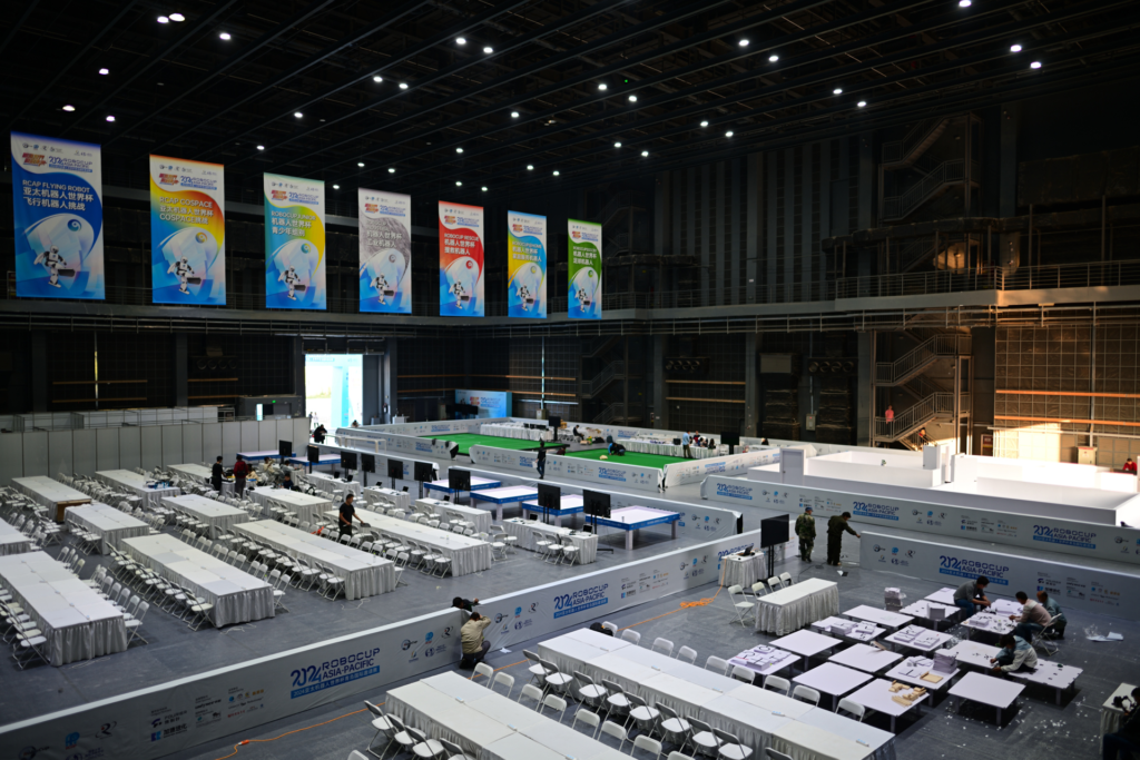 Indoor venue setup for RoboCup Asia-Pacific 2022 featuring competition zones, banners, and preparation activity.