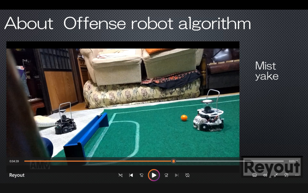 Paused video frame from Reyout Japan’s RoboCup Asia-Pacific 2022 online submission, showing two robots and an orange ball on a green soccer field.