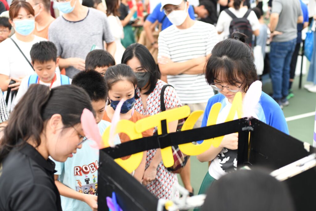 Crowd at Club Automatica booth with claw machine at Raffles Institution Open House 2023
